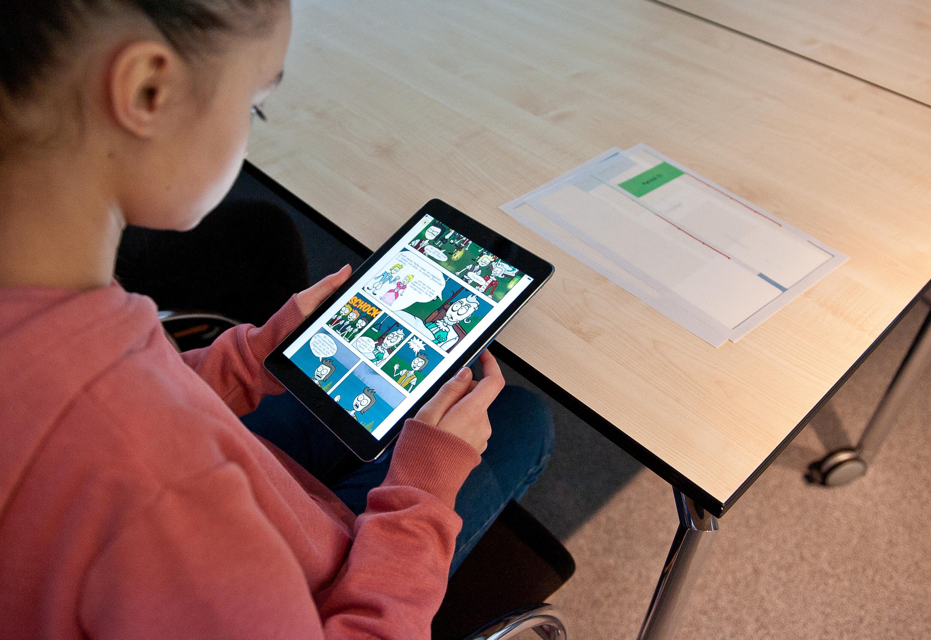 Mädchen sitzt mit Handy am Tisch