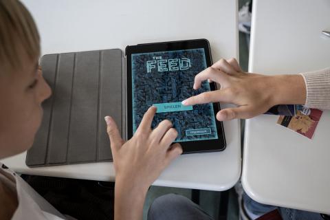 Zwei Schüler tippen gemeinsam auf den "Spielen" Button im Startmenü des Games