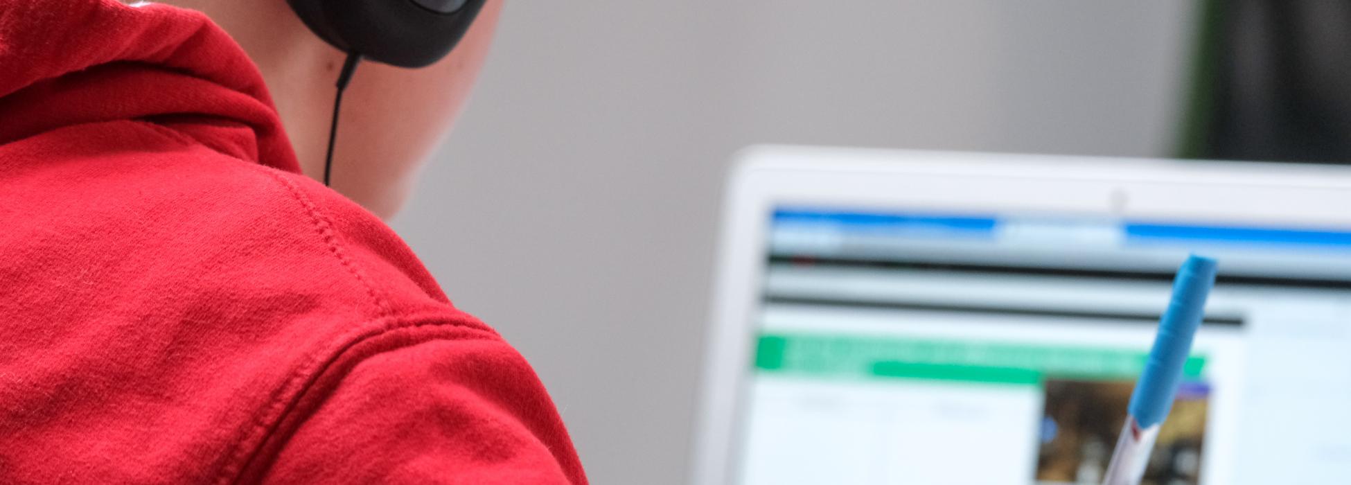 Symbolbild E-Learning in Schulen Kind mit Kopfhörern vor Laptop
